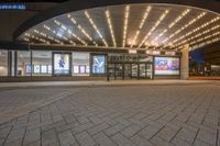 a large building with a big awning and windows lit up at night time with bright lights