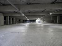 an empty parking garage with several lights on overhead lighting area next to parking space and storage boxes