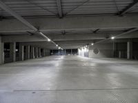 an empty parking garage with several lights on overhead lighting area next to parking space and storage boxes