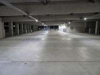 an empty parking garage with several lights on overhead lighting area next to parking space and storage boxes