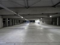 an empty parking garage with several lights on overhead lighting area next to parking space and storage boxes