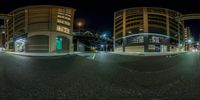 an intersection with two buildings at night time in city, all lit up with green lights