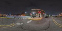 the image shows a night time view of a intersection with street lights and some traffic