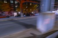 cars and trucks drive down the street next to an urban bridge at night time,