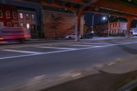 cars and trucks drive down the street next to an urban bridge at night time,