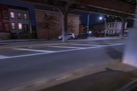 cars and trucks drive down the street next to an urban bridge at night time,