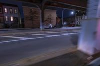 cars and trucks drive down the street next to an urban bridge at night time,