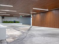 a large empty parking garage in the middle of town, with many plants in cement boxes on the concrete