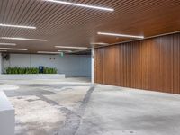 a large empty parking garage in the middle of town, with many plants in cement boxes on the concrete