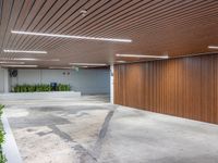 a large empty parking garage in the middle of town, with many plants in cement boxes on the concrete