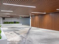 a large empty parking garage in the middle of town, with many plants in cement boxes on the concrete