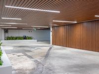 a large empty parking garage in the middle of town, with many plants in cement boxes on the concrete