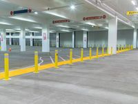 the interior of a large building is empty, filled with parking meters, yellow poles and safety barriers