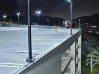 an empty parking lot with two parked vans at night time in the dark with street lamps