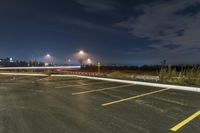 an empty parking lot with lots of cars driving on it and lights on at night