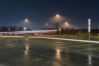 an empty parking lot with lots of cars driving on it and lights on at night