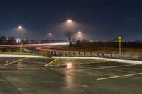 an empty parking lot with lots of cars driving on it and lights on at night