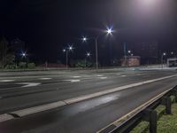 a night time photograph of the empty road with a traffic light on the corner and buildings in the background