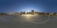 a very large empty parking lot in front of some city buildings at night time as seen from a high angle