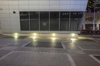 a skateboarder rides down the street on pavement outside an office building at night