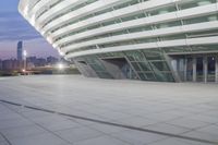 a person on a skateboard rides by a white building in a city park at night