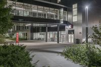 a very large office building surrounded by plants and trees at night time with low lights