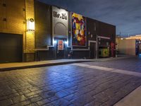 a night time street scene with an illuminated store front and people walking on the sidewalk