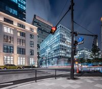 a street view with some buildings around it in the city at night time, and a traffic light