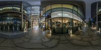 a mirror image shows an office and building at night time, along with people on the sidewalk