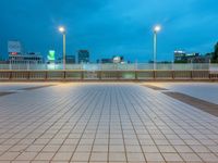 people standing on a subway platform with many buildings in the background at night light in tokyo