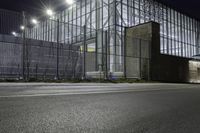 a photo of the outside of an industrial building at night time and a person is standing under the lights