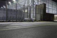 a photo of the outside of an industrial building at night time and a person is standing under the lights