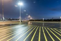 a fork lift is driving through a parking lot at night time with lights on in the background