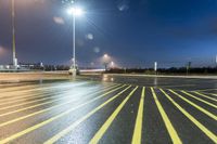 a fork lift is driving through a parking lot at night time with lights on in the background