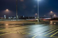 a fork lift is driving through a parking lot at night time with lights on in the background