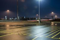 a fork lift is driving through a parking lot at night time with lights on in the background