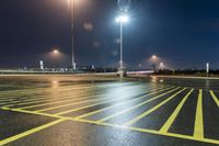 a fork lift is driving through a parking lot at night time with lights on in the background