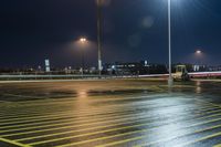 a fork lift is driving through a parking lot at night time with lights on in the background