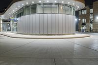 a photo of the outside of a large building at night time with lights on it