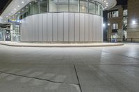 a photo of the outside of a large building at night time with lights on it