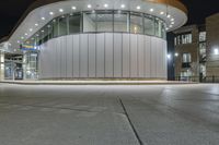 a photo of the outside of a large building at night time with lights on it