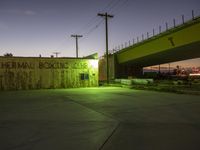 a very bright and nice looking building with a road bridge behind it at night time