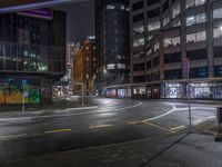 a night shot of an empty street at night in the city with lots of tall buildings