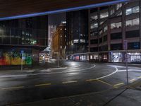 a night shot of an empty street at night in the city with lots of tall buildings