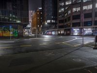 a night shot of an empty street at night in the city with lots of tall buildings