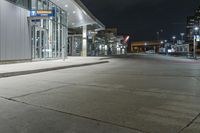 night time photograph of empty city street with lit buildings in distance in urban area at night