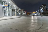 night time photograph of empty city street with lit buildings in distance in urban area at night