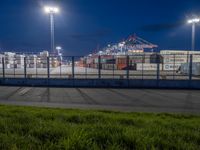 the view from a walkway over a parking lot on a night time, looking at a port container terminal