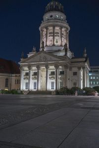 an image of night time view of a church with columns and clocktowers on top