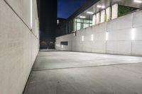 the large concrete wall has been illuminated by recessed lights at night on either side of it